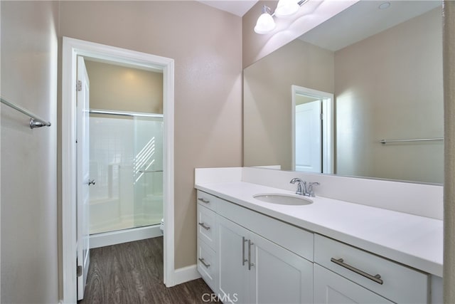 bathroom with a shower stall, wood finished floors, and vanity