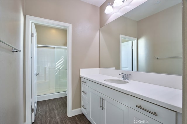 full bathroom with vanity, baseboards, a shower stall, and wood finished floors