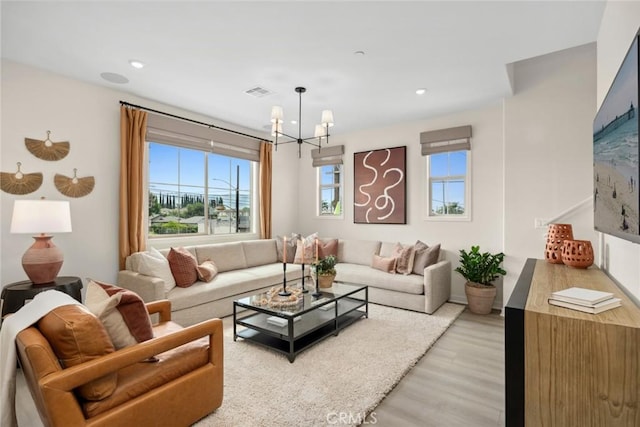 living room featuring plenty of natural light, a chandelier, light wood-type flooring, and recessed lighting