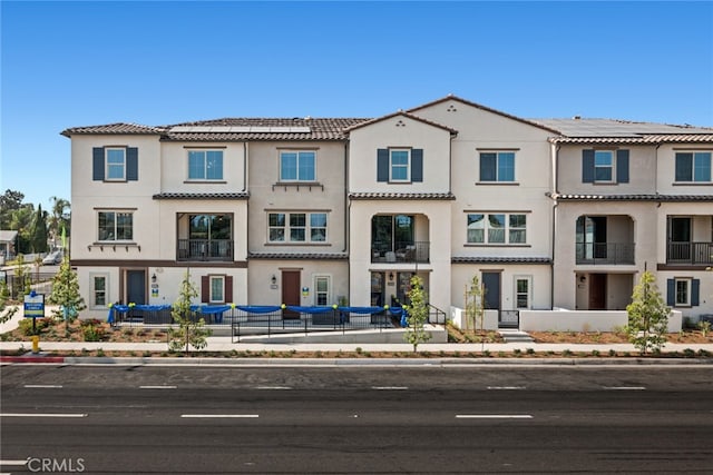 multi unit property with stucco siding and a tiled roof