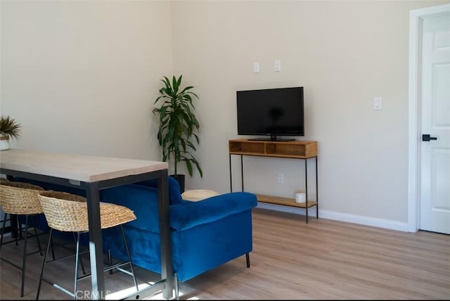 living area with baseboards and wood finished floors