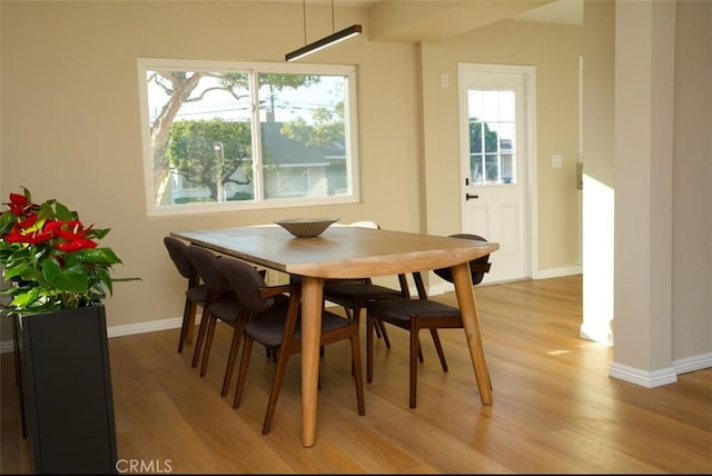 dining space with light wood-style flooring and baseboards