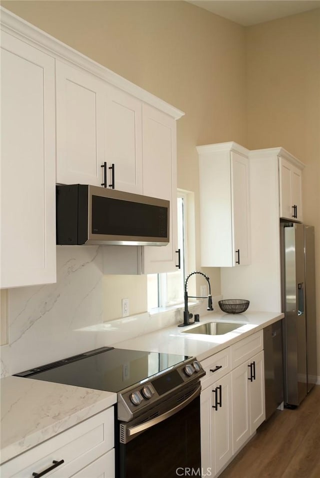 kitchen with light wood-style flooring, appliances with stainless steel finishes, white cabinets, and a sink