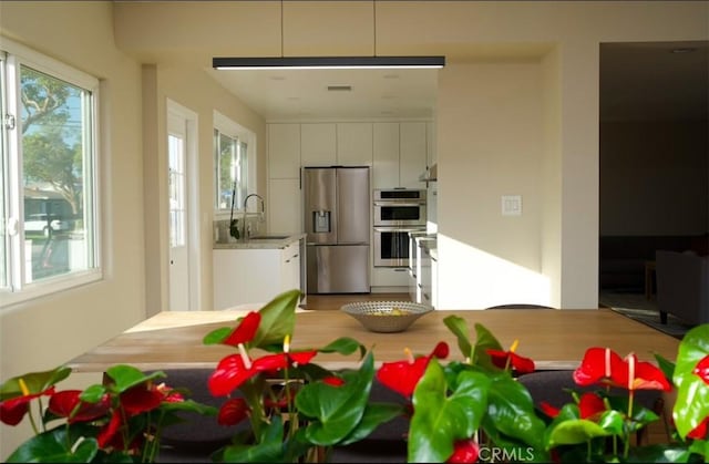 kitchen with white cabinets, light wood-style flooring, appliances with stainless steel finishes, light countertops, and a sink