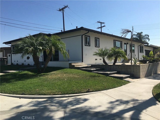 view of front of home with entry steps, a front lawn, and stucco siding