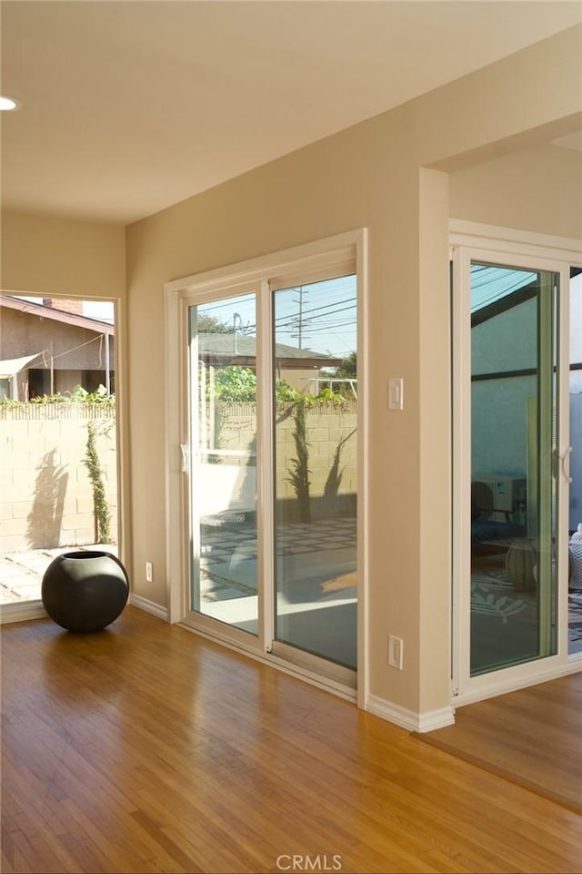 doorway featuring baseboards and wood finished floors