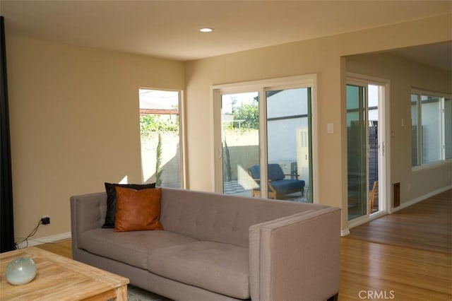 living area with baseboards, wood finished floors, and recessed lighting