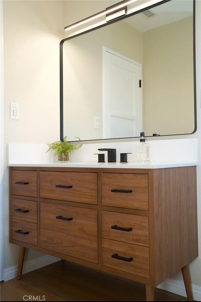 bathroom with vanity, baseboards, and wood finished floors