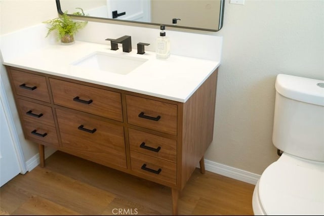 bathroom featuring wood finished floors, vanity, toilet, and baseboards