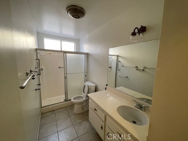 full bath featuring vanity, a shower stall, toilet, and tile patterned floors