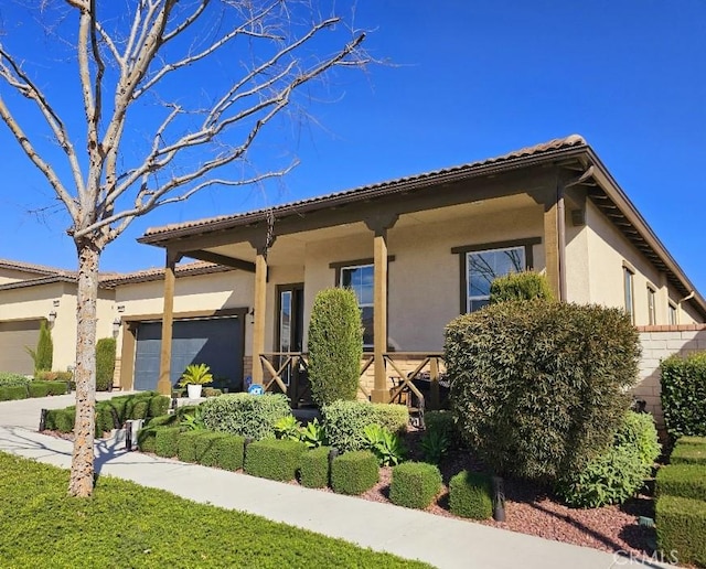 view of front of home with stucco siding, a garage, driveway, and a tile roof