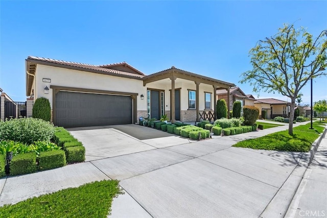 mediterranean / spanish house featuring an attached garage, a tiled roof, driveway, and stucco siding