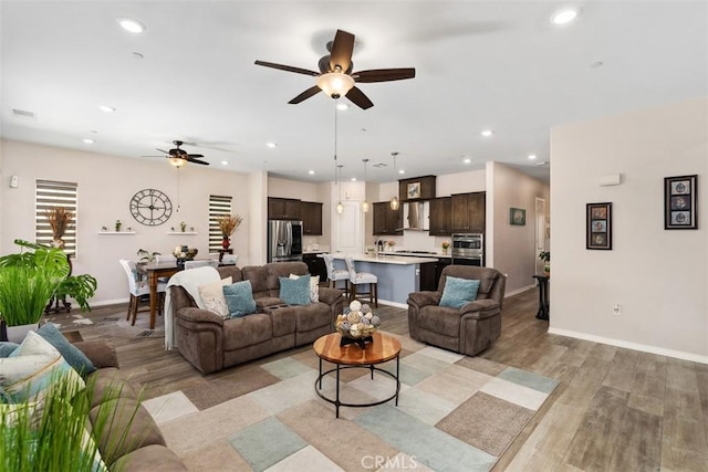 living room featuring light wood-style flooring, baseboards, recessed lighting, and ceiling fan