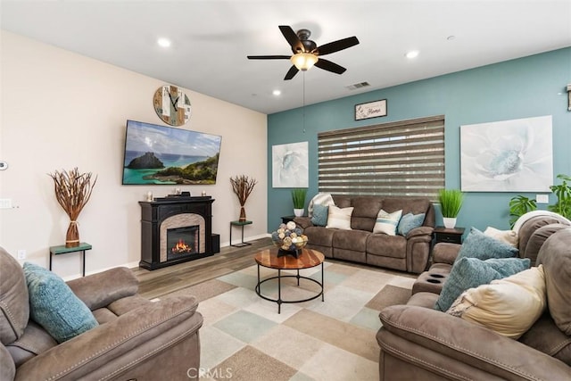 living room featuring a glass covered fireplace, visible vents, recessed lighting, light wood-style floors, and ceiling fan