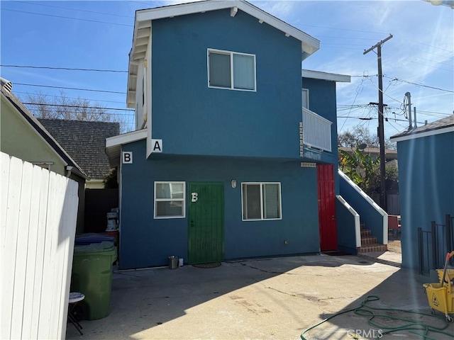 rear view of property with a patio, fence, and stucco siding