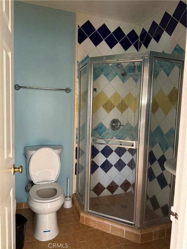 bathroom featuring a shower stall, toilet, and tile patterned floors