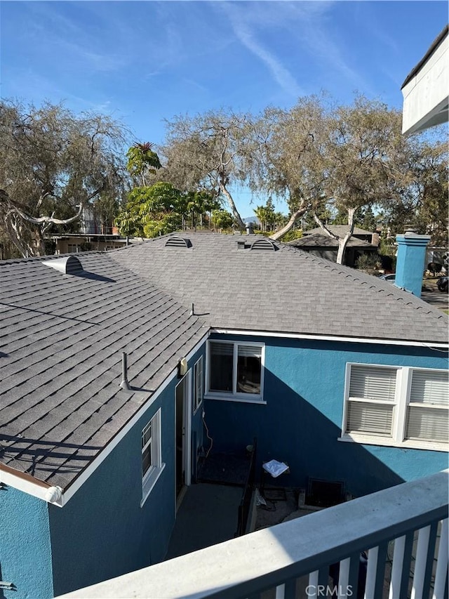 exterior space with roof with shingles and stucco siding