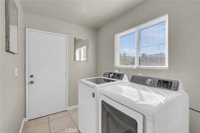 washroom with laundry area, light tile patterned flooring, washing machine and dryer, and baseboards