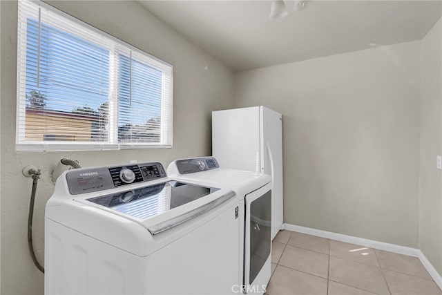 laundry area featuring laundry area, baseboards, separate washer and dryer, and light tile patterned flooring