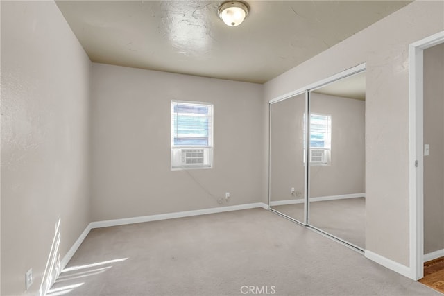 unfurnished bedroom featuring multiple windows, carpet flooring, a closet, and baseboards