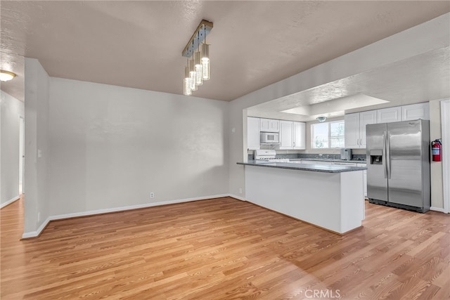 kitchen with light wood finished floors, white cabinets, white microwave, a peninsula, and stainless steel refrigerator with ice dispenser