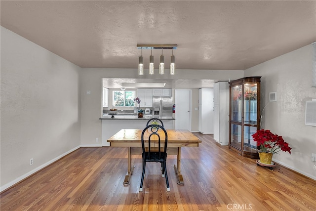 dining area with visible vents, a textured ceiling, baseboards, and wood finished floors