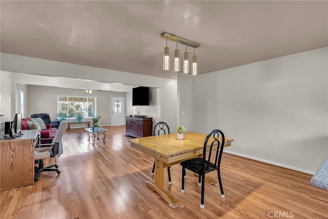 dining space featuring light wood-style floors and baseboards