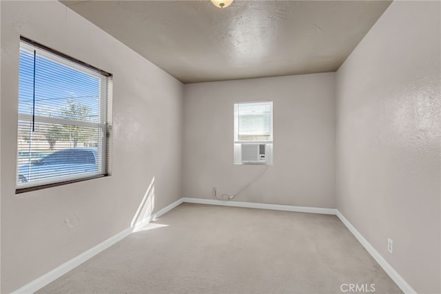 unfurnished room featuring light carpet, baseboards, and cooling unit