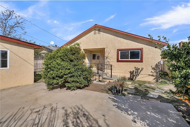 bungalow-style home with a patio area, fence, and stucco siding