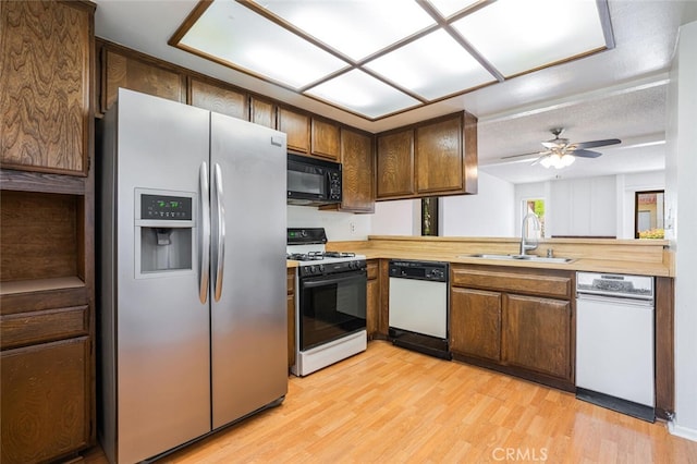 kitchen with range with gas stovetop, stainless steel refrigerator with ice dispenser, a sink, black microwave, and dishwasher