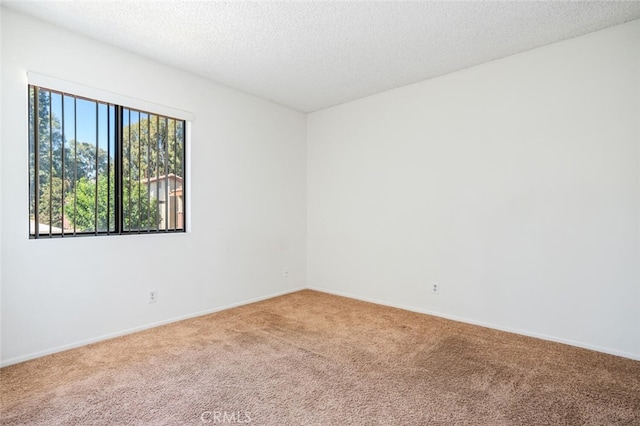 carpeted empty room featuring baseboards and a textured ceiling