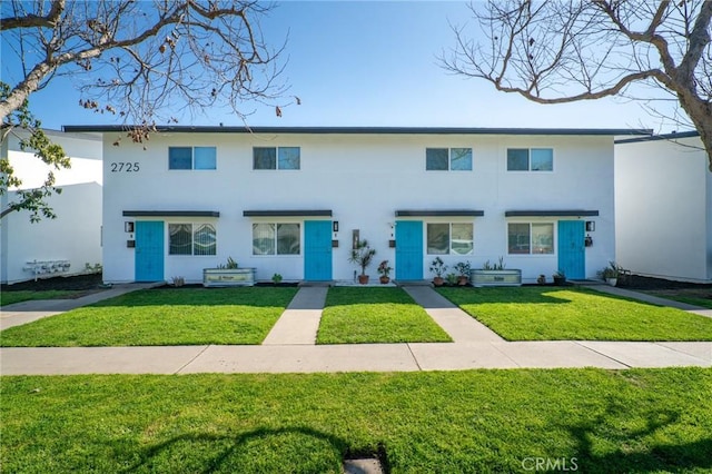 view of property with a front lawn and stucco siding