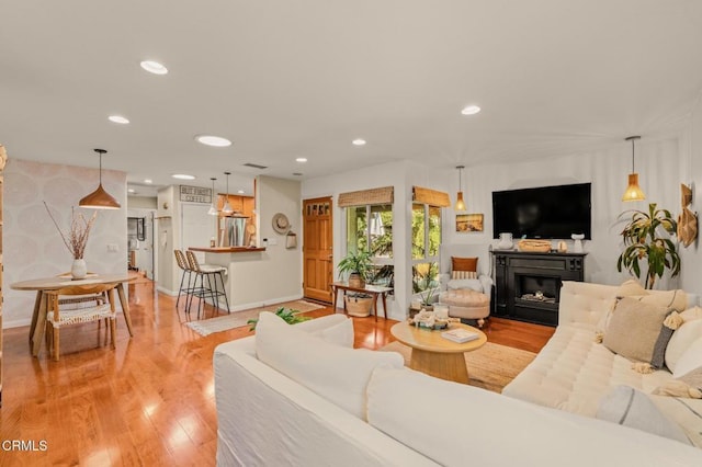 living area with light wood-type flooring, a fireplace, baseboards, and recessed lighting