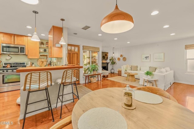 dining area featuring visible vents, a fireplace, light wood-style flooring, and recessed lighting