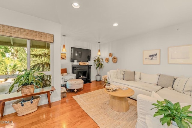 living area with recessed lighting, light wood-type flooring, and a fireplace