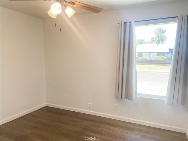 spare room featuring a healthy amount of sunlight, dark wood finished floors, and baseboards