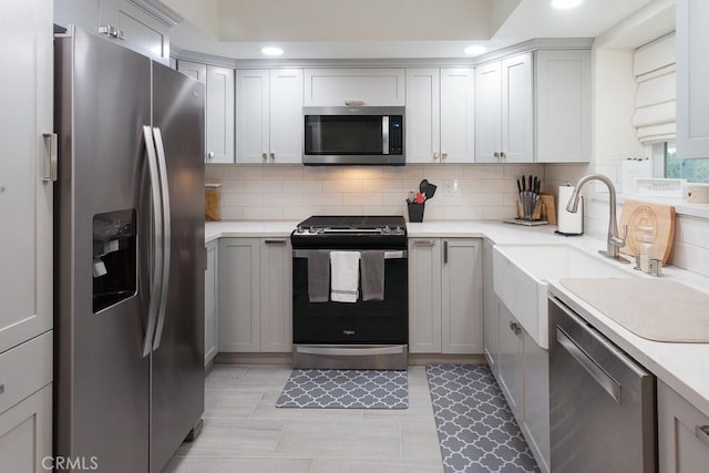 kitchen featuring stainless steel appliances, recessed lighting, light countertops, decorative backsplash, and a sink