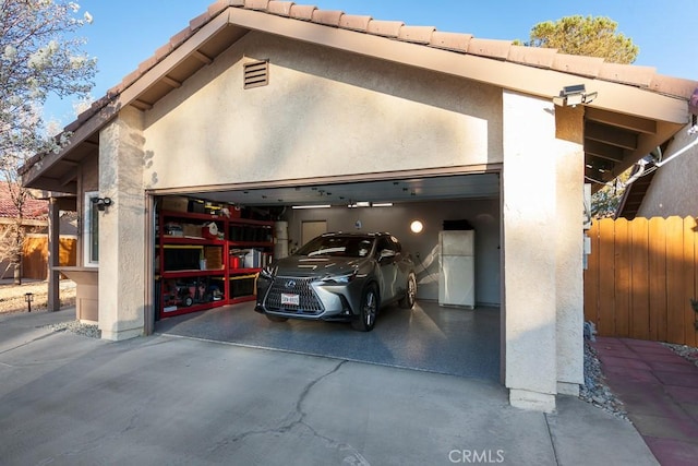 exterior space with fence, concrete driveway, and freestanding refrigerator