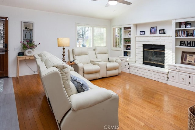 living room with hardwood / wood-style flooring, ceiling fan, a brick fireplace, and vaulted ceiling