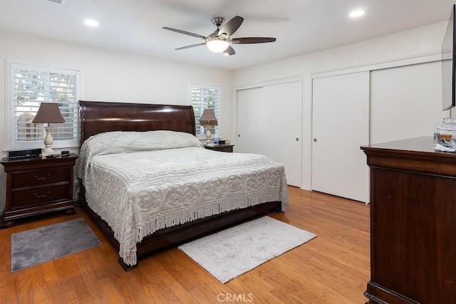 bedroom featuring light wood-style floors, recessed lighting, a ceiling fan, and two closets