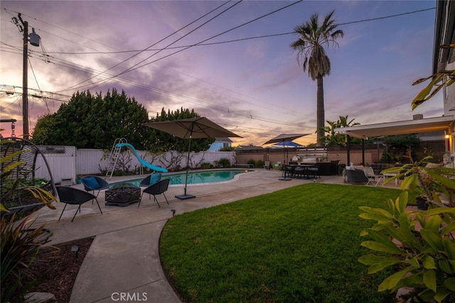 view of swimming pool featuring a yard, a water slide, a patio, and a fenced backyard