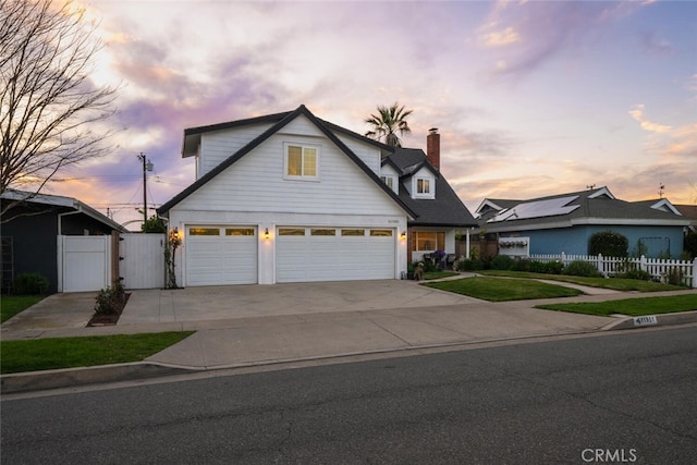 view of front of house featuring driveway, a chimney, an attached garage, a gate, and fence