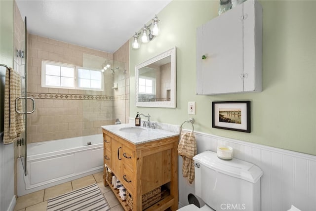 bathroom featuring bathtub / shower combination, toilet, wainscoting, vanity, and tile patterned floors