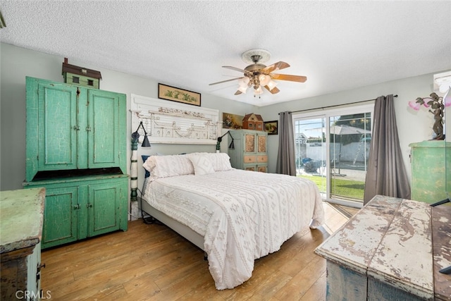 bedroom featuring a ceiling fan, access to outside, light wood-style flooring, and a textured ceiling