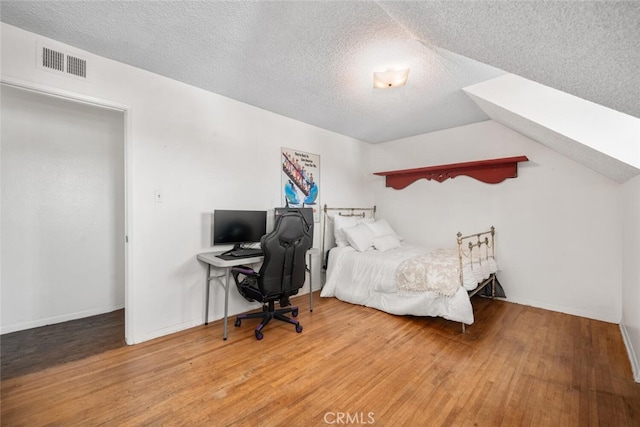 bedroom featuring visible vents, a textured ceiling, and wood finished floors