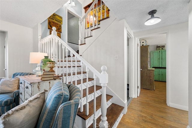 stairs with a textured ceiling, baseboards, and hardwood / wood-style flooring