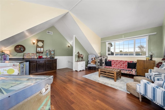 living room featuring a wainscoted wall, visible vents, vaulted ceiling, and wood finished floors