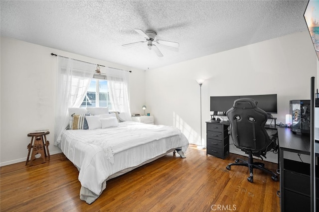 bedroom featuring a textured ceiling, wood finished floors, a ceiling fan, and baseboards