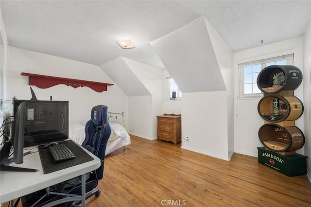 office area featuring lofted ceiling, a textured ceiling, and wood finished floors