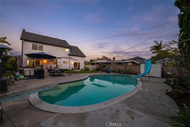 view of swimming pool featuring a fenced in pool, a water slide, a patio, and fence